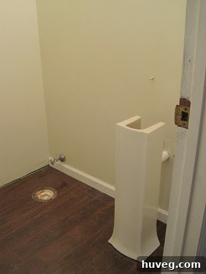 Partially renovated powder room with new flooring and primed walls, awaiting final touches.