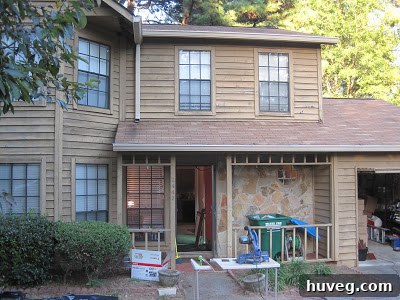 Home exterior during kitchen flooring installation with tools and materials outside.