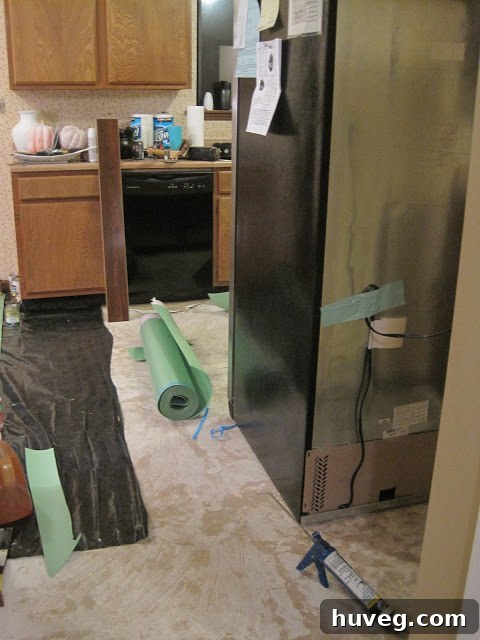 Kitchen floor with some new flooring installed, appliances moved.
