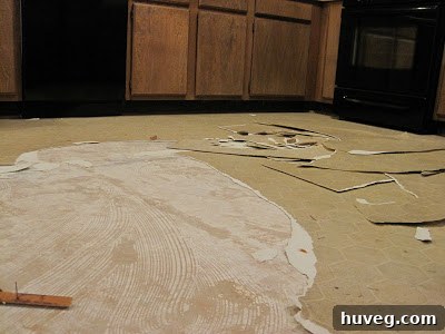 Close-up of old linoleum being peeled away from kitchen floor