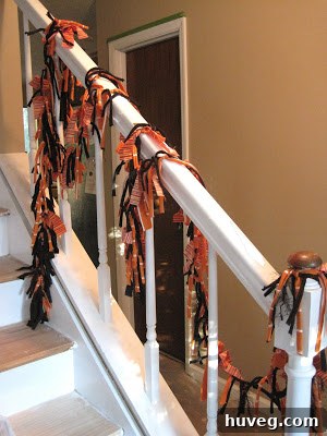 Hands in the process of tying fabric strips onto a ribbon, demonstrating the creation of a DIY Halloween wreath with orange and white striped fabric.