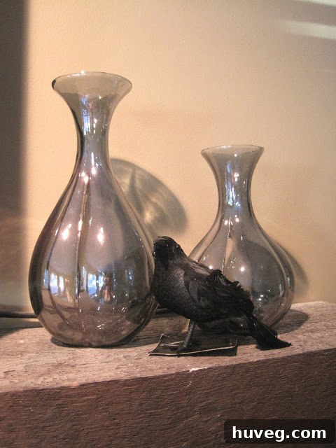 Two elegant smokey purple vases on a mantel, awaiting Halloween embellishments like spiders or dark florals.