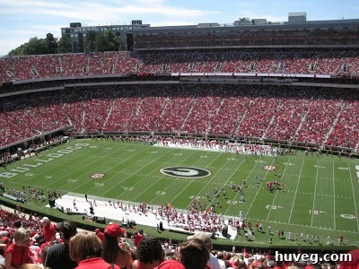 A packed Sanford Stadium, a sea of red and black fans cheering during a UGA football game.
