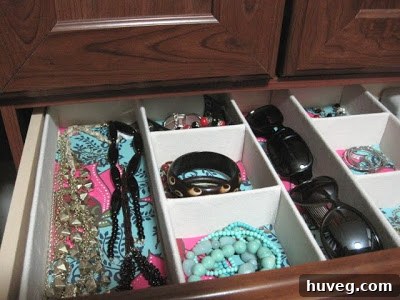 Jewelry drawer with organizers and decorative paper lining, sunglasses in the gap