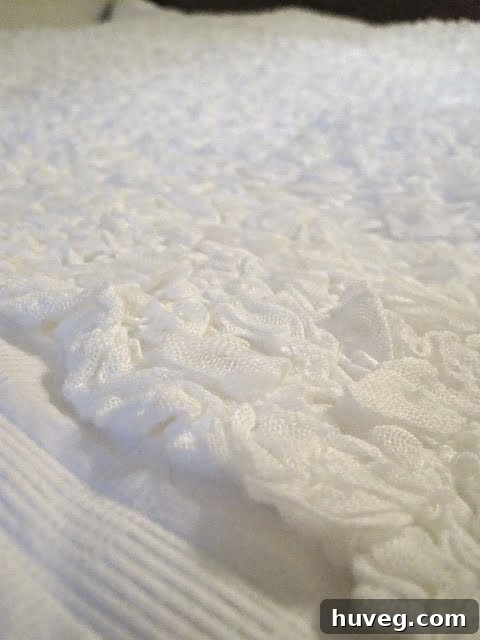 Close-up of a white bed with wooden headboard and matching dresser in a newly painted gray guest bedroom.