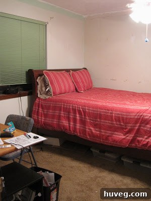 Current state of the guest bedroom before renovation, showing cluttered furniture