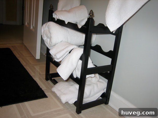 Creative bathroom storage solution: a repurposed black wine rack holding neatly rolled white towels, adding both elegance and functionality to the space.