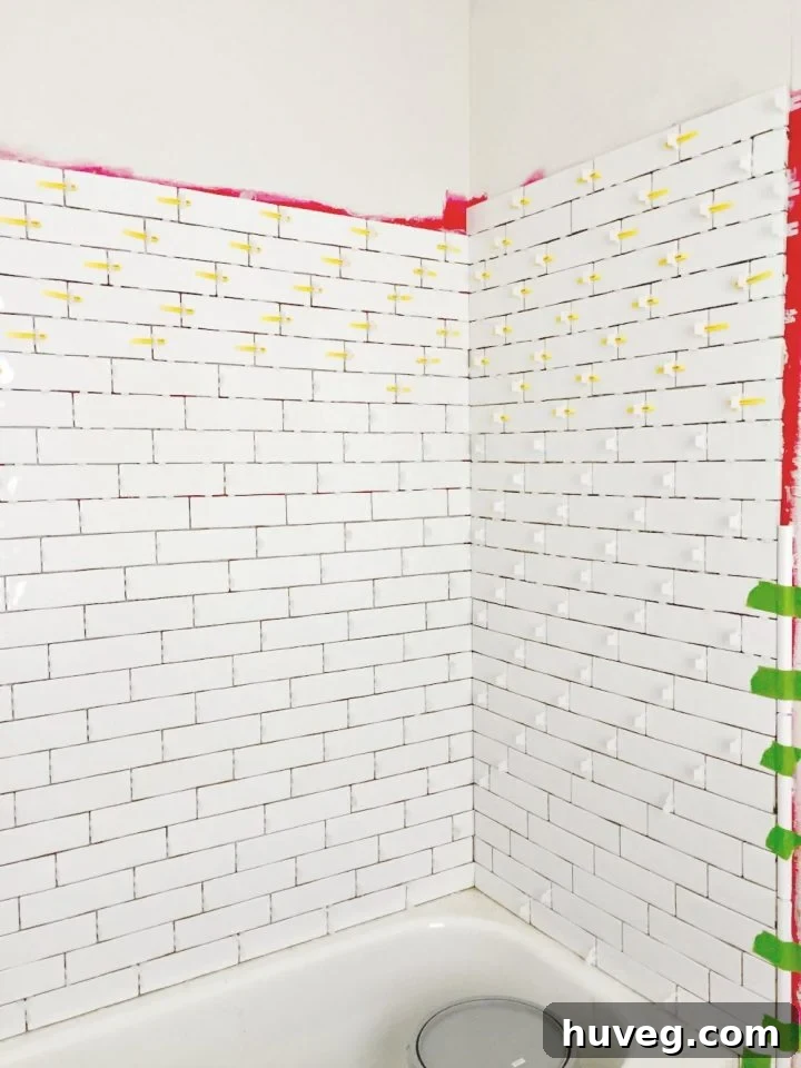 Tiling master bathroom tub surround with long white subway tile