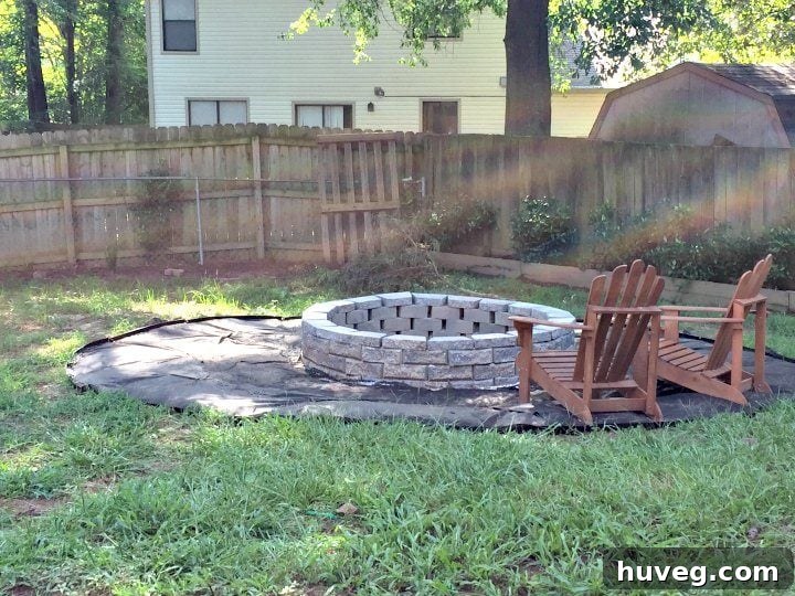 My finished DIY stone fire pit, complete with a landscaping ring and two inviting Adirondack chairs, ready for outdoor gatherings.