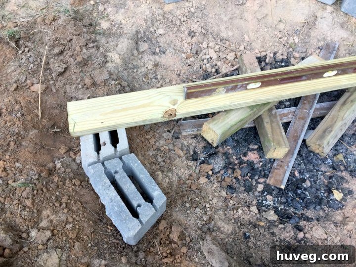 To level the fire pit base, I used a straight board with a level placed on top, ensuring the foundation was perfectly flat across the entire diameter.