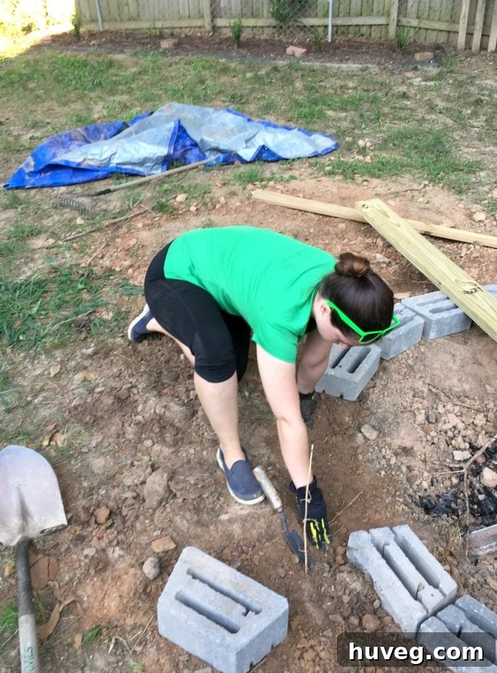 Here I am, wearing a green shirt, carefully measuring and leveling each stone for the fire pit base to ensure a stable foundation.
