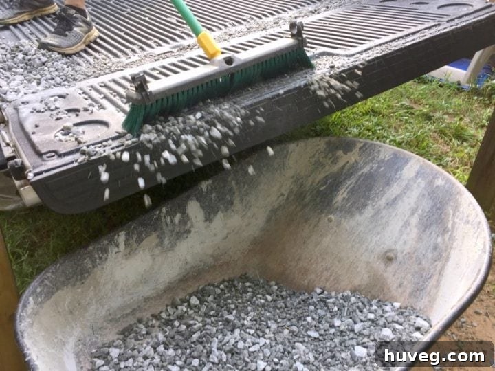 Using a push broom to sweep remaining gravel into a wheelbarrow