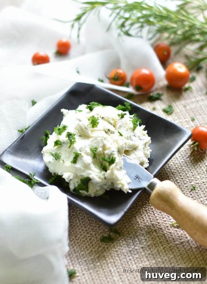 Creamy herbed goat cheese mixture being spread on toasted crostini slices.