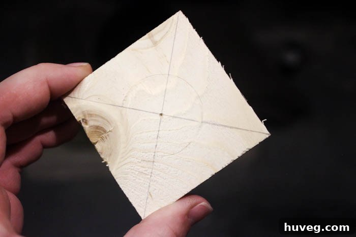 Close-up of a wood block with diagonal lines drawn from corner to corner, indicating the center point for drilling.