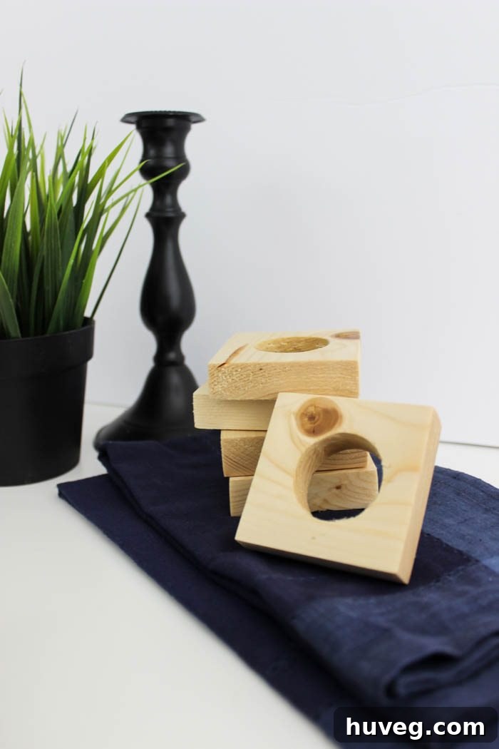 Close-up shot of a white napkin threaded through a natural wood square napkin ring, highlighting the clean lines and finish.