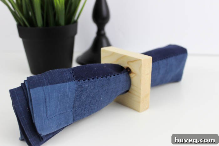 Three finished modern square napkin rings displayed on a wooden surface, ready for use, emphasizing their simple beauty.