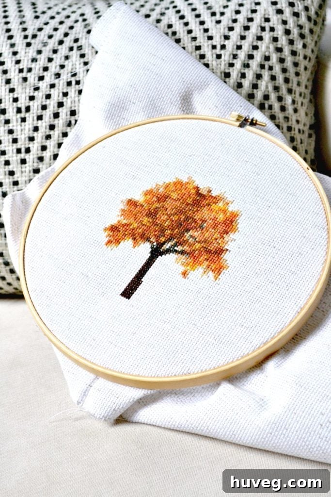Close-up of a finished fall tree cross stitch framed, showcasing the intricate details of the autumn foliage.