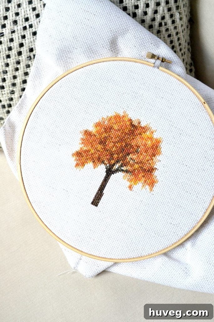 Detailed shot of a fall tree cross stitch, showcasing vibrant autumn colors and simple x-stitches.