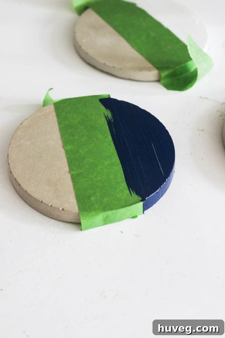 Personalize your concrete coasters with paint using painter's tape for clean lines.