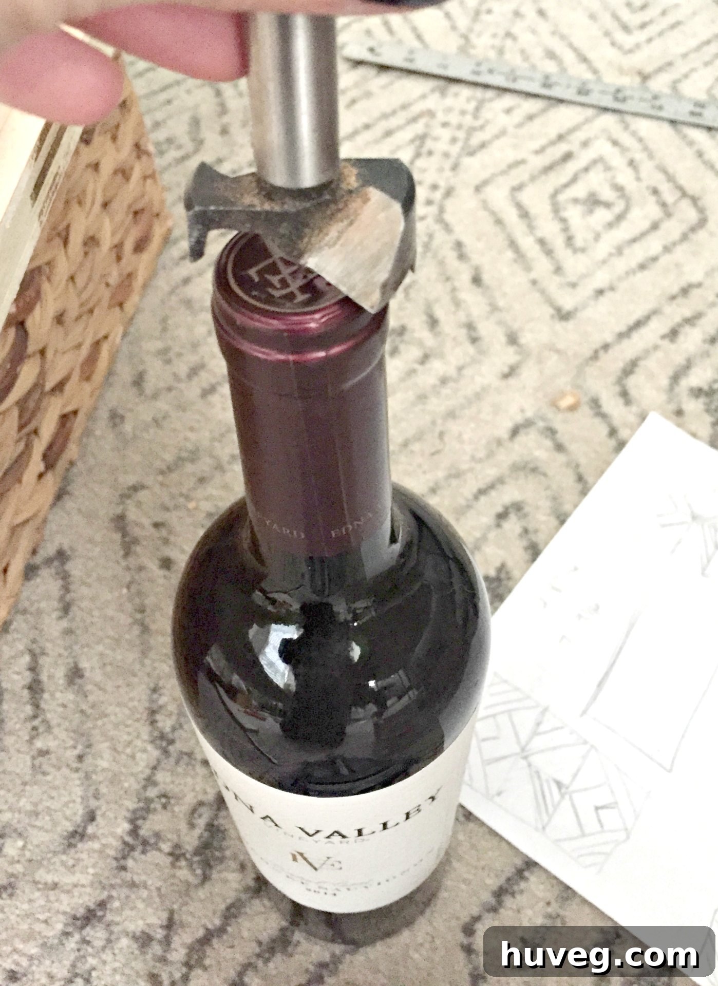 Visually checking a Forstner drill bit size against a wine bottle neck for fit