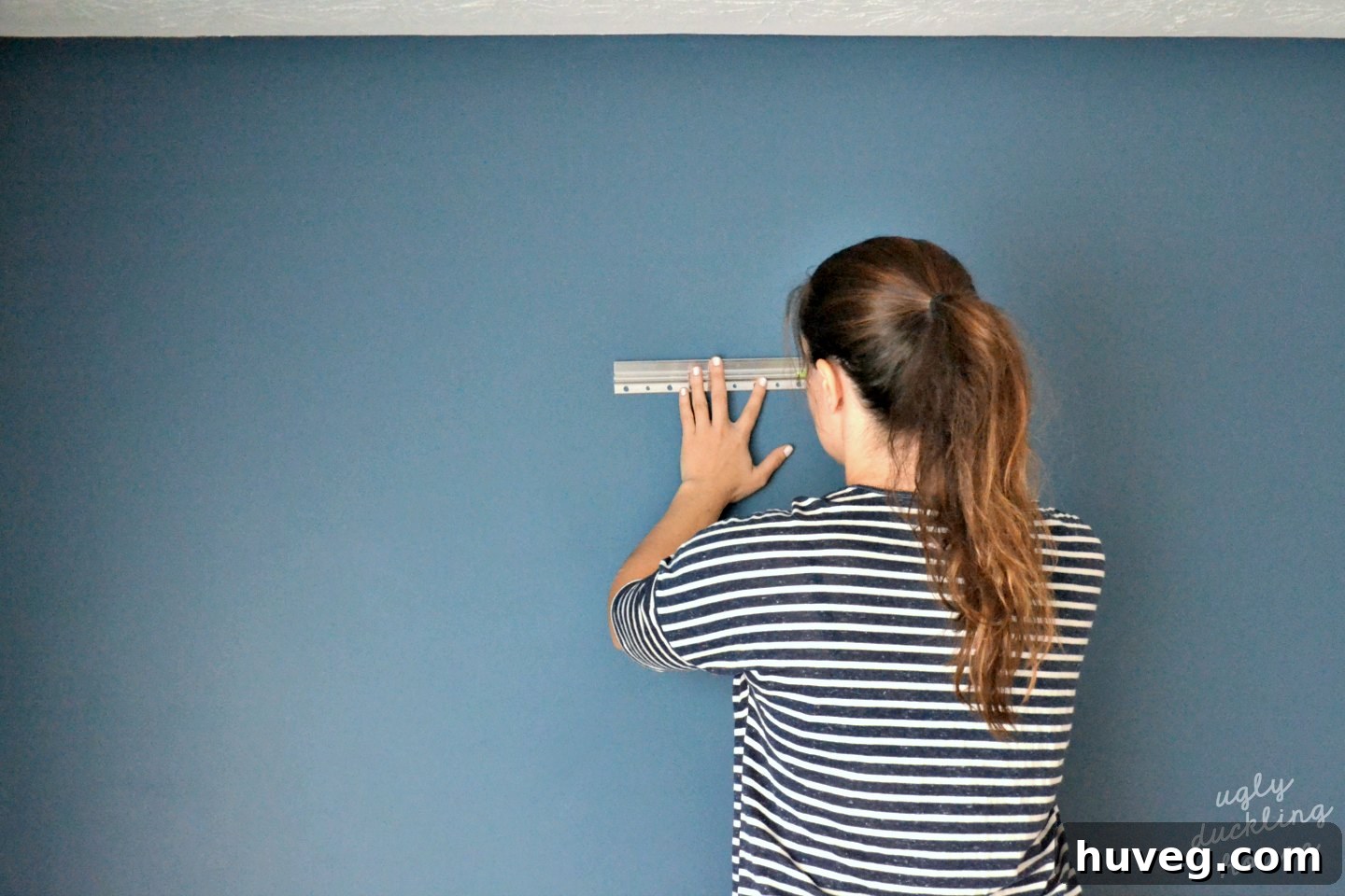 Measuring and leveling a metal French cleat on the wall for wine rack mounting