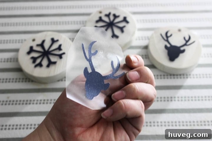 Applying iron-on vinyl design onto a wooden ornament with an iron