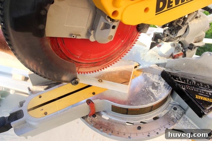 Using a miter saw set at a 45-degree angle to make the initial corner cut on a 2x4 for a triangle tea light holder.