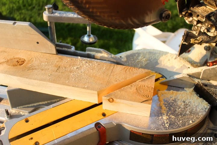 Performing a second straight cut with the miter saw at 90 degrees to efficiently produce an identical wooden triangle, minimizing waste.