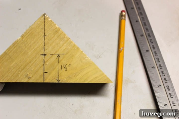 Using a speed square and pencil to accurately mark the precise center point on a wooden triangle for drilling the tea light recess.