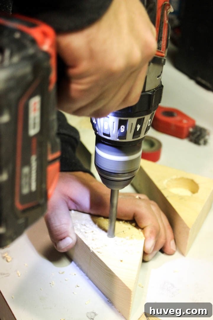 Drilling a small, clean pilot hole into the accurately marked center of the wooden triangle using a 5/16-inch brad point drill bit.