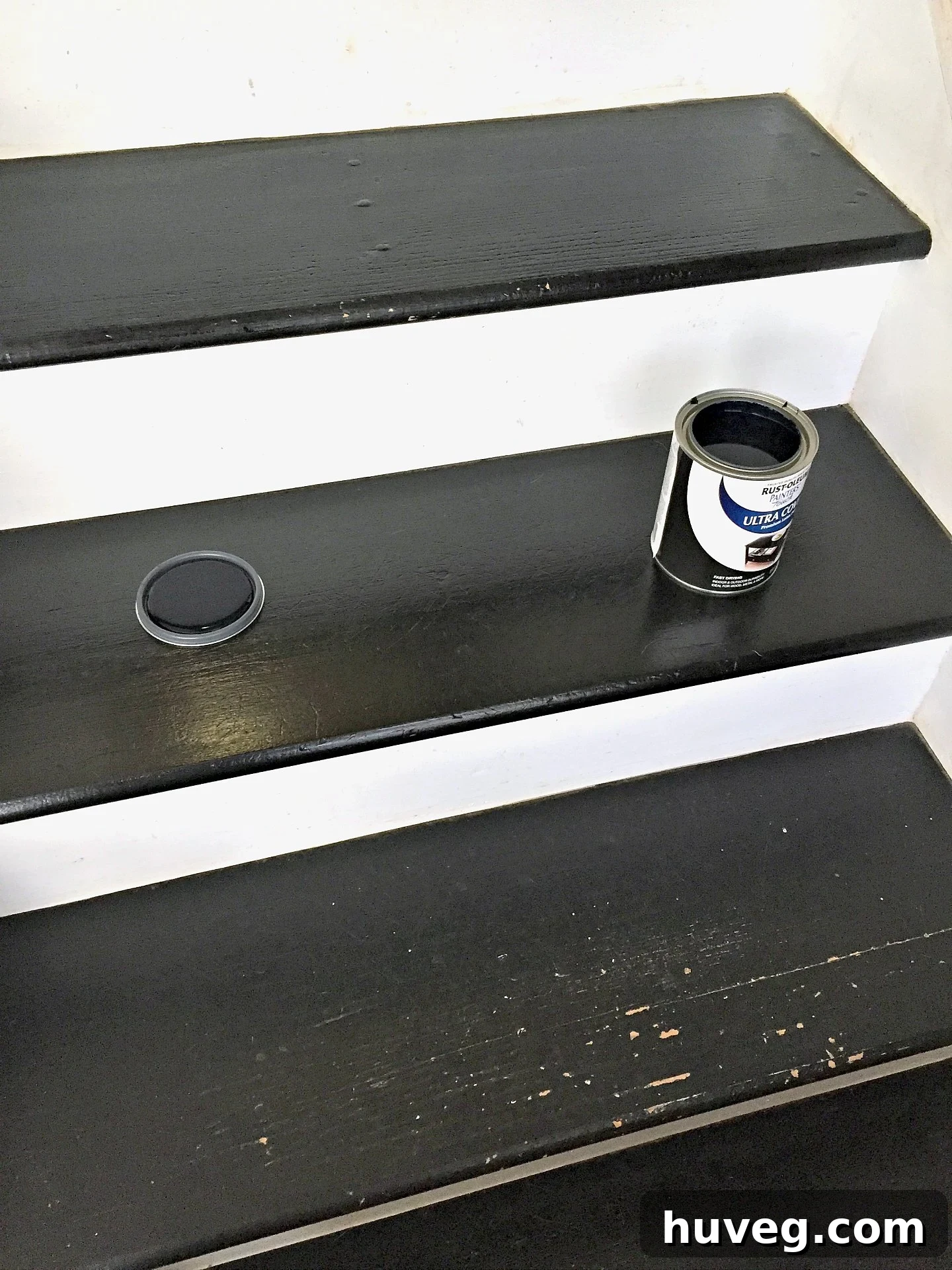 A close-up shot of hands carefully touching up scratches on the black and white staircase, illustrating the attention to detail in home maintenance.