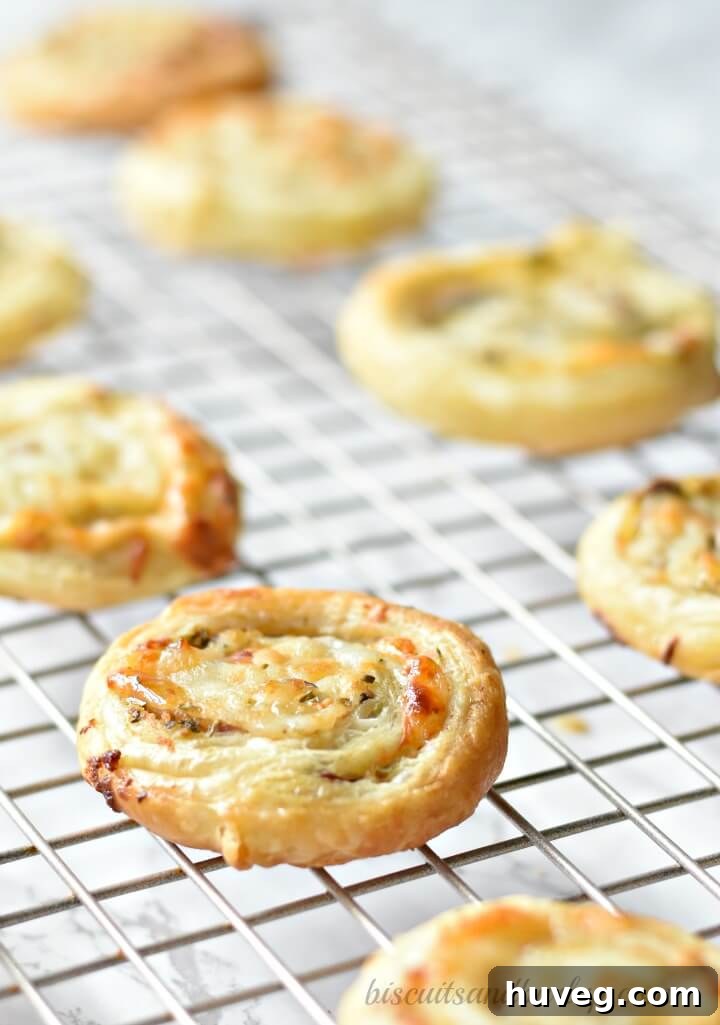 Freshly baked puff pastry pinwheels cooling on a wire rack, showcasing their golden-brown, flaky texture and spiral layers.