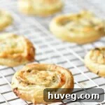 Golden puff pastry pinwheels on a white plate, ready for serving.