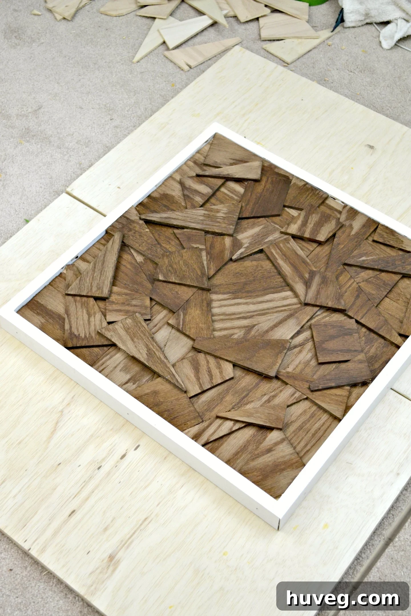 After staining the wood offcuts within the pristine white frame, I allowed them to dry on several pieces of salvaged lumber, ensuring optimal airflow.