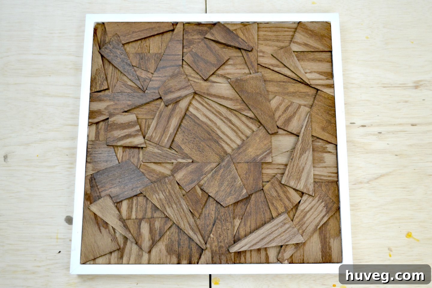 The dark-stained wood, encased in its white frame, is carefully drying atop several pieces of reclaimed lumber, awaiting its next transformation.