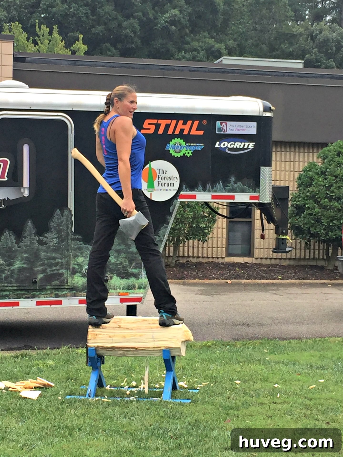Axe Woman Logger performing a log chopping demonstration on a log between her feet