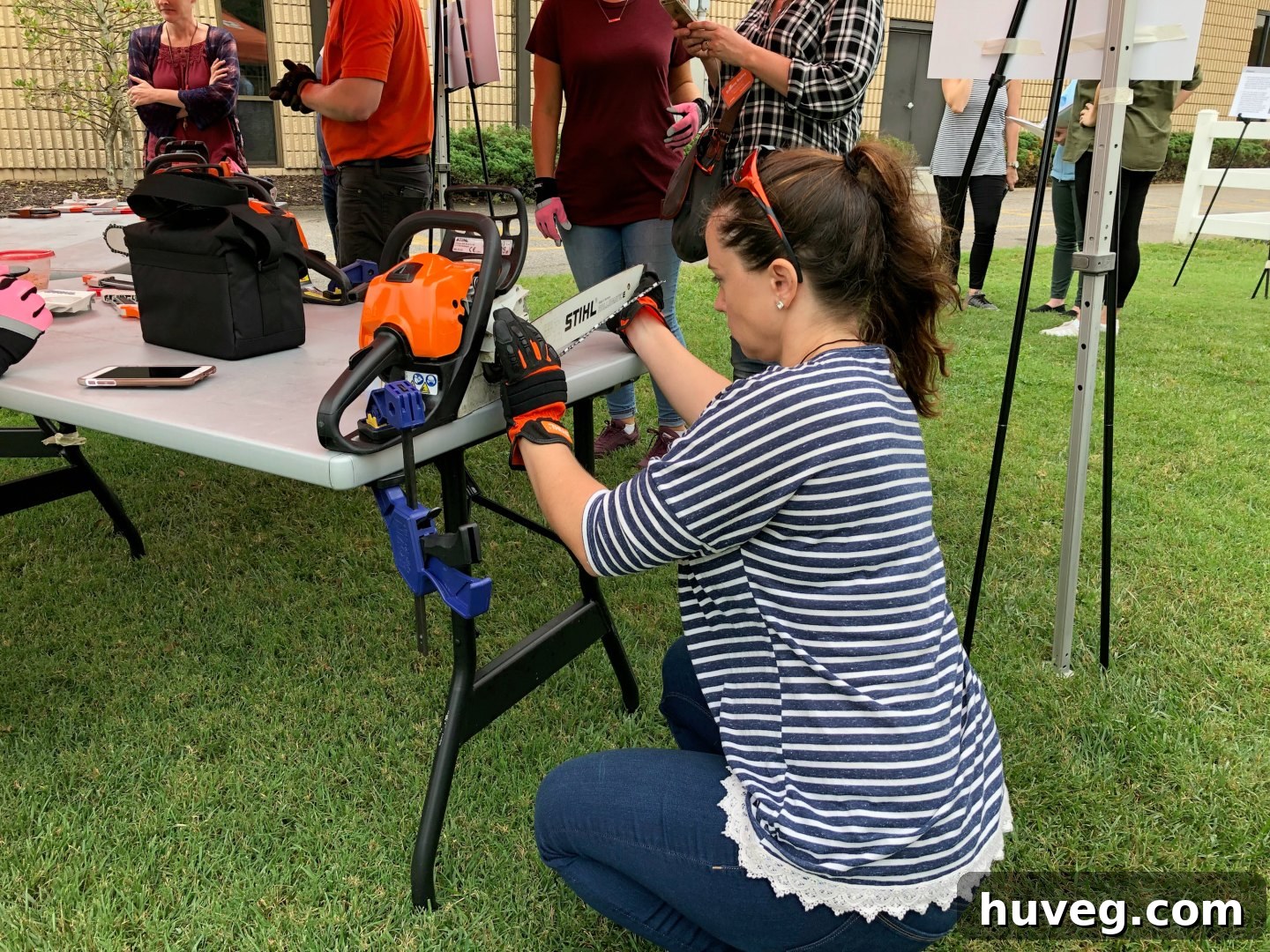 Woman carefully learning to fit a new chain onto a STIHL chainsaw