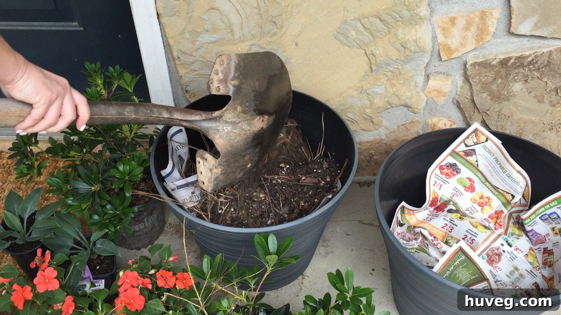 Layering newspaper and potting soil over plastic bottles in a container garden