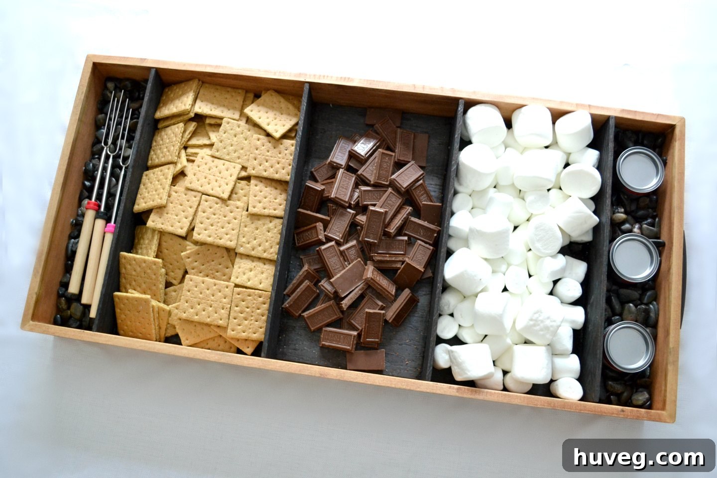 A view of the charred wood s’mores tray from above, with roasting sticks and Sterno cans