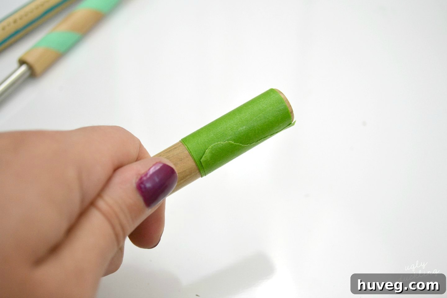 Using painter's tape to achieve straight, clean lines when applying craft paint to roasting sticks