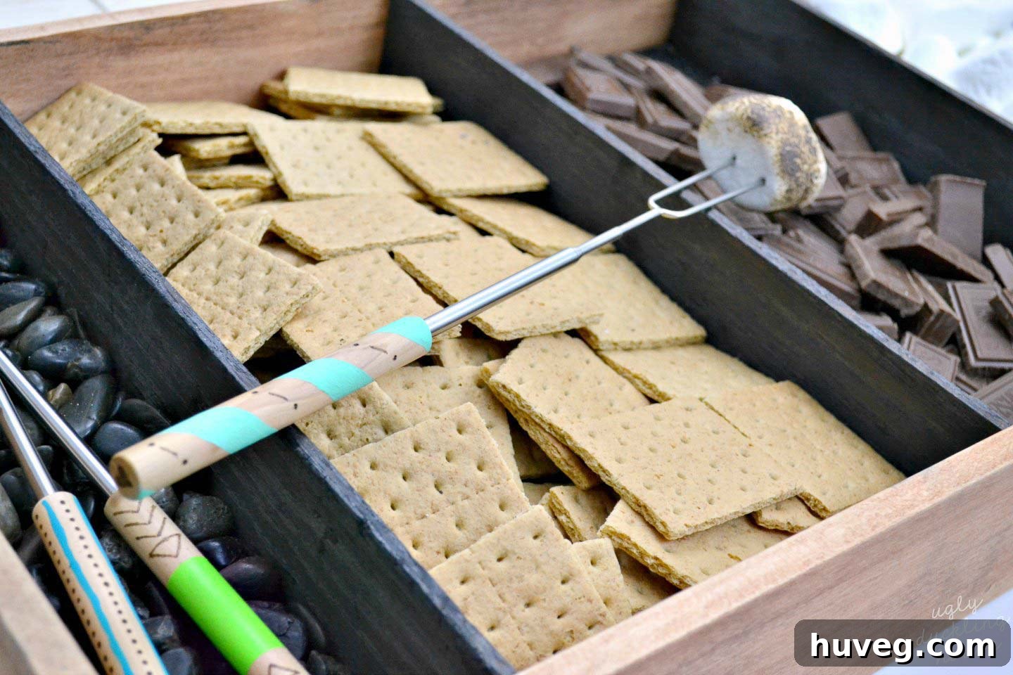Personalized roasting sticks ready for marshmallows, paired with a charred wood s'mores tray