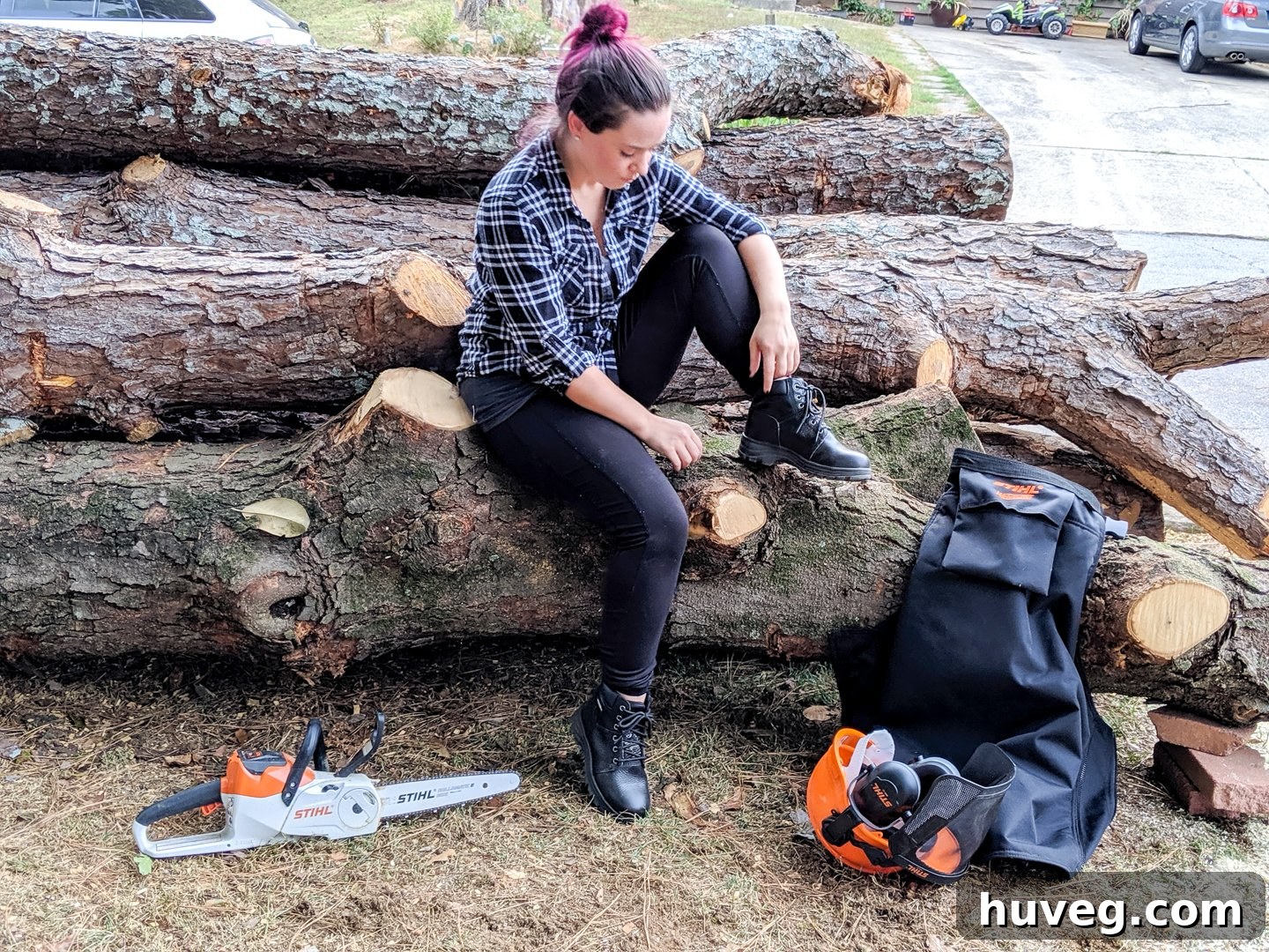 Sarah Fogle, fully equipped with chainsaw safety gear including helmet, chaps, and glasses, preparing for wood milling.
