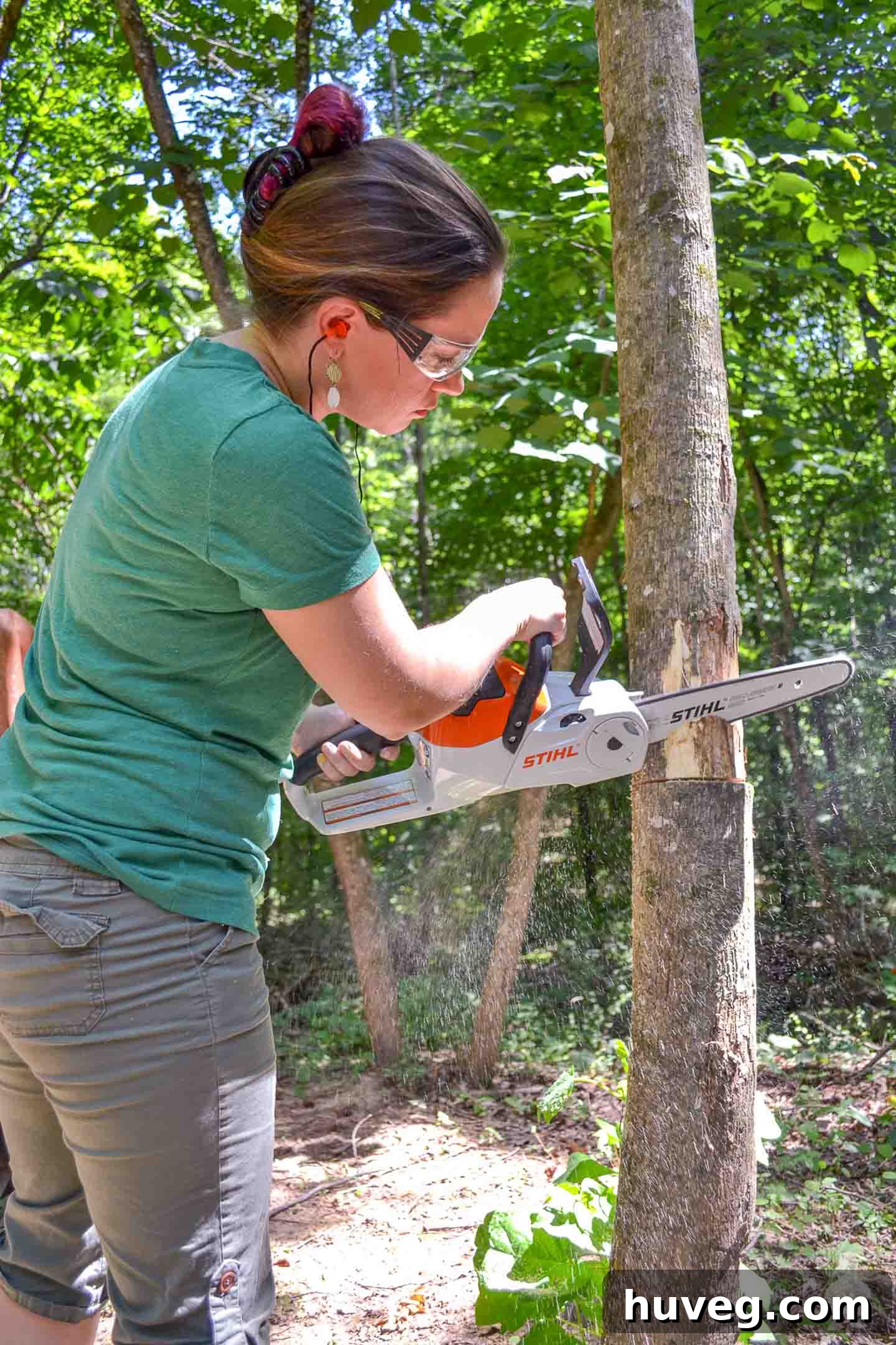 The author safely cutting down a dead tree at waist level using a chainsaw, demonstrating comfortable posture.