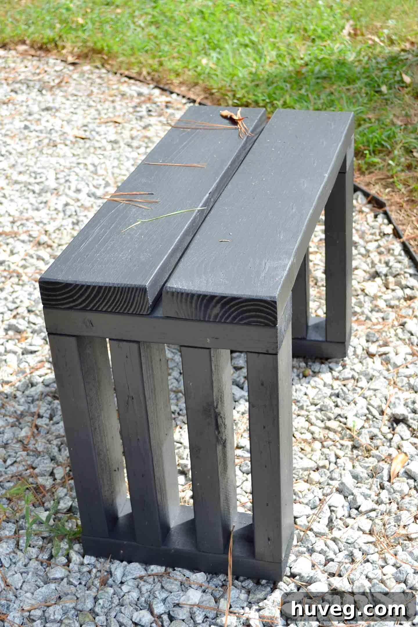Scrap wood garden bench seat with new black paint, providing extra seating around a fire pit and matching other outdoor furniture