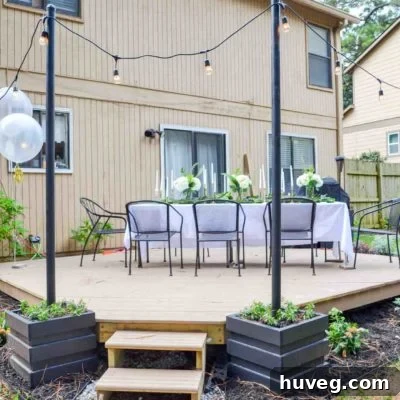 Outdoor dining table setup on floating deck with black light poles and hanging outdoor lights for ambient evening lighting