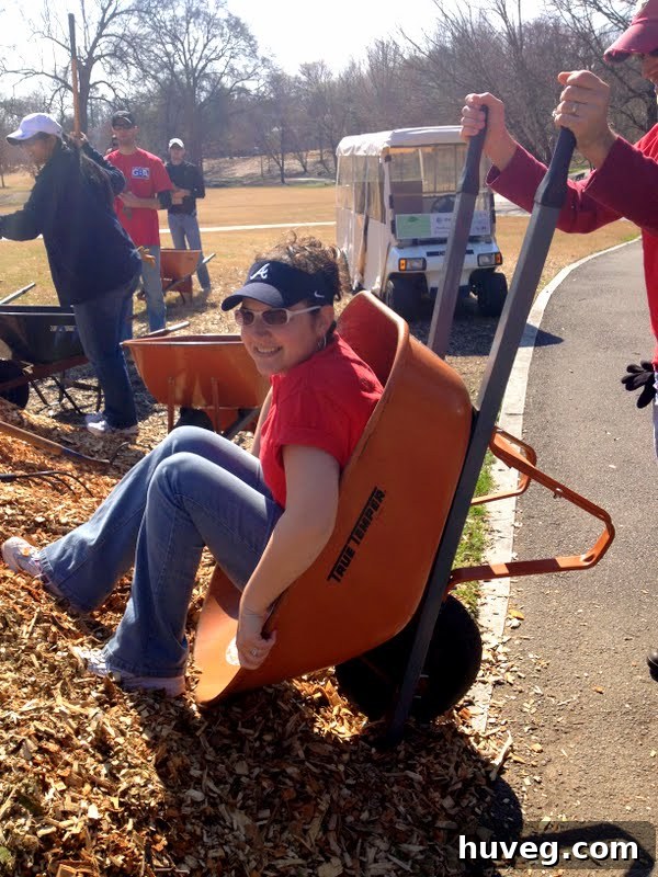 Person pushing a wheelbarrow full of mulch through a park