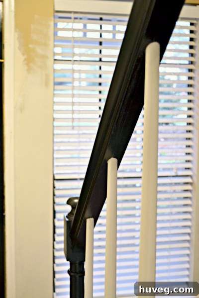 Close-up of a meticulously painted black handrail against a light wall, demonstrating attention to detail in a home renovation project.