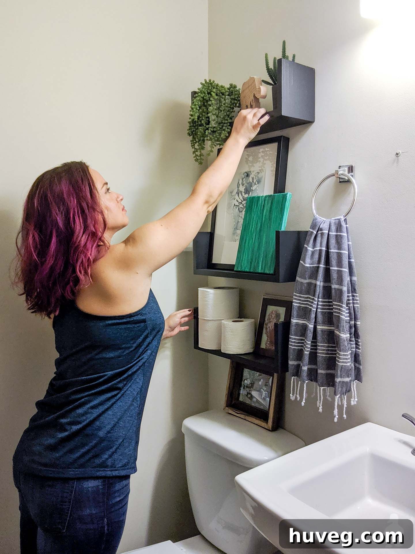 Stylish floating U-shaped shelves made from wood, styled with plants, picture frames, and essentials in a powder room.