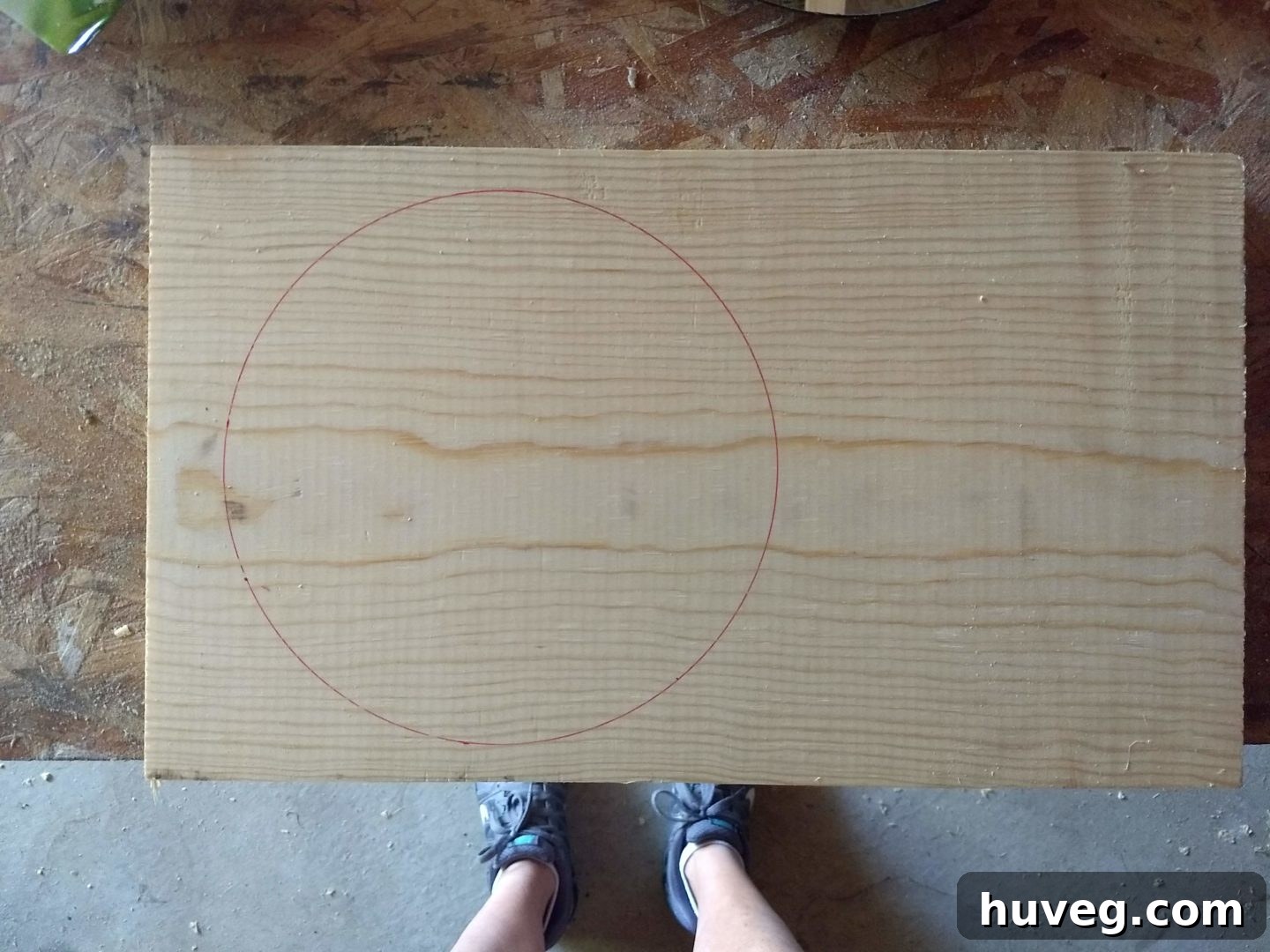 Tracing the round mirror onto the wood board to establish the initial diameter for the frame, a crucial first step in DIY mirror framing.