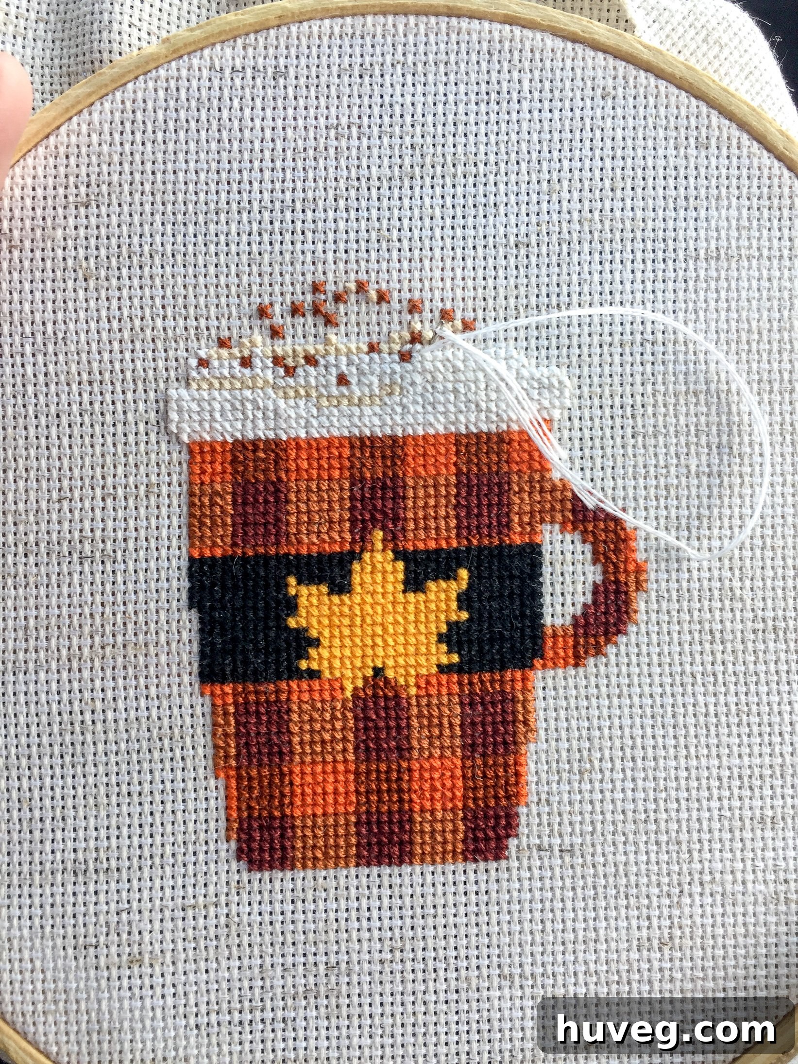 Close-up of a cross stitch project, showing the intricate stitching on fabric.